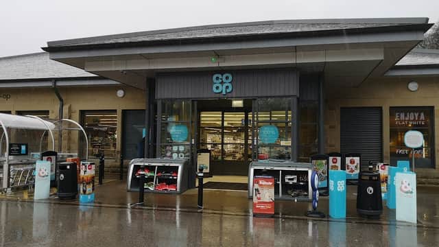 Co-op Food store entrance with shopping carts, outdoor displays, and a rainy atmosphere in Holmfirth, Yorkshire.