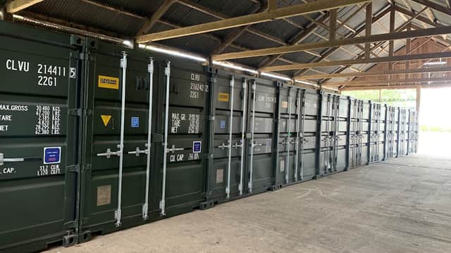 Storage containers lined up under a wooden roof in Chapel Hill Storage, Thornborough, North Yorkshire.