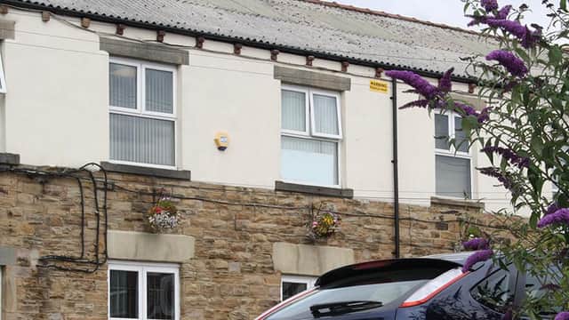 Carr Mills Business Centre features stone and white exterior, window boxes with flowers, and parked cars in front.