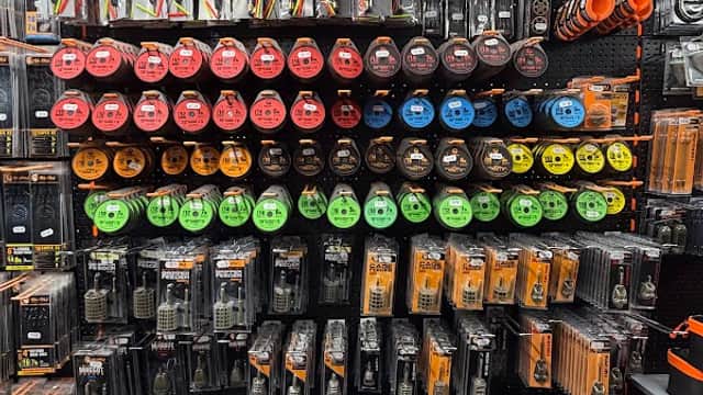 A wall display of fishing gear, featuring various lines, hooks, and tools in vibrant packaging at Aston Park Angling Centre.