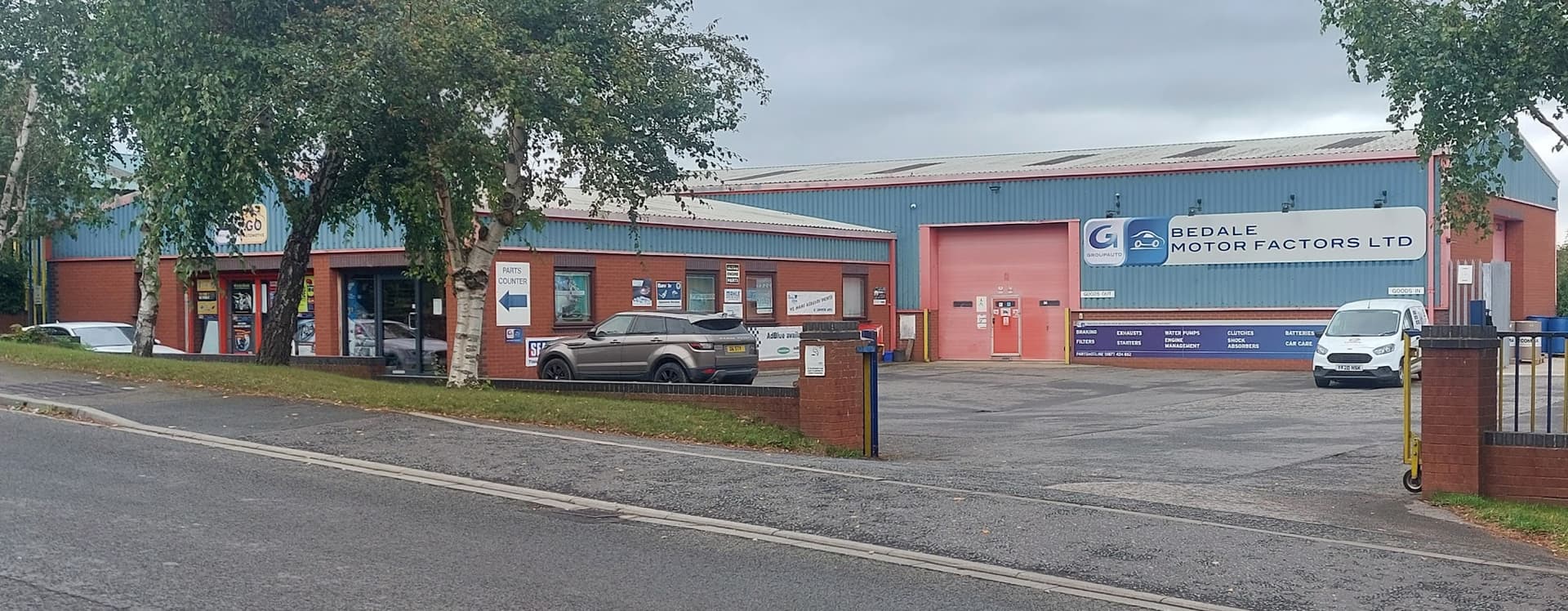 Bedale Motor Factors Ltd building with signage, parked cars, and surrounding greenery in Leeming Bar, Yorkshire.