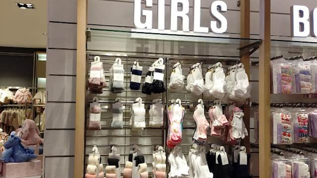 Display of girls' clothing and accessories on shelves, featuring various colors and styles in a retail setting.