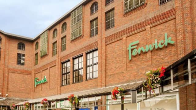 Brick building with large windows, "Fenwick" signage, and flower baskets adorning the entrance in Dewsbury, Yorkshire.