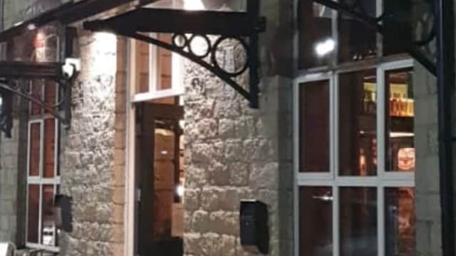 Vine Bar entrance with illuminated sign, outdoor seating, and stone facade in West Vale, Yorkshire.