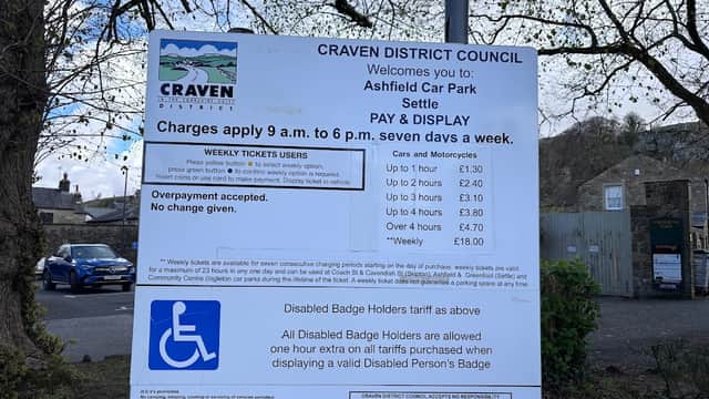 Sign detailing parking charges and regulations at Ashfield Car Park, Settle, with information on disabled badge holders.