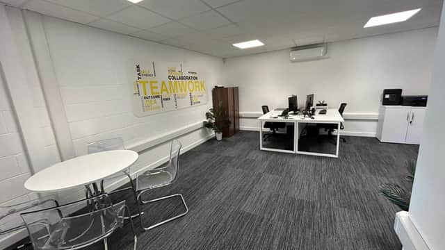 Modern office space featuring a white desk, chairs, a round table, and a wall mural emphasizing teamwork.