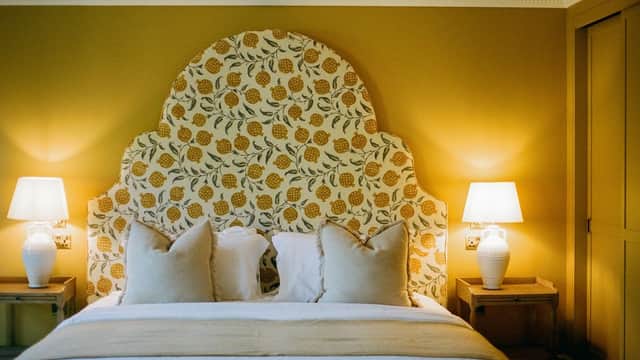 Elegant bedroom with a floral headboard, soft pillows, warm lighting, and stylish bedside tables.
