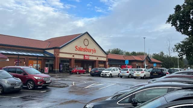 Sainsbury's storefront at Colton Retail Park, with parked cars and cloudy skies in the background.