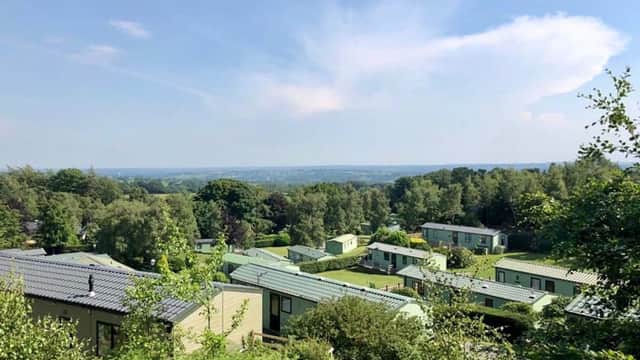 Scenic view of Warren Forest Park with green lodges nestled among trees and rolling hills under a blue sky.