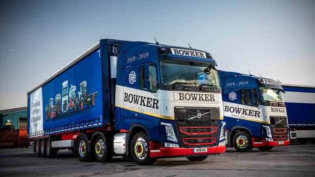 Two blue and white Bowker Group trucks parked, showcasing the company logo and a commemorative design for 1919-2019.