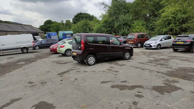 Cote Green Car Park in Deepcar, Yorkshire, with multiple parked cars and greenery in the background under cloudy skies.