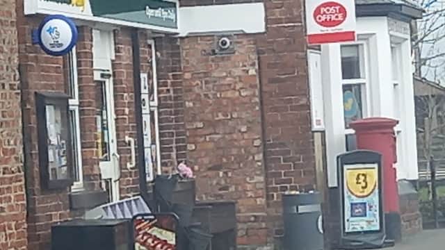 Morrisons Daily grocers with a Post Office sign, red post box, and a display of snacks outside on a brick building.