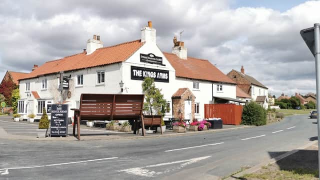 The Kings Arms pub in Sandhutton, Yorkshire, with a white exterior, red roof, and outdoor seating area.
