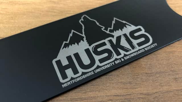A black bar blade featuring the logo of Hertfordshire University Ski & Snowboard Society with mountains and a wolf.