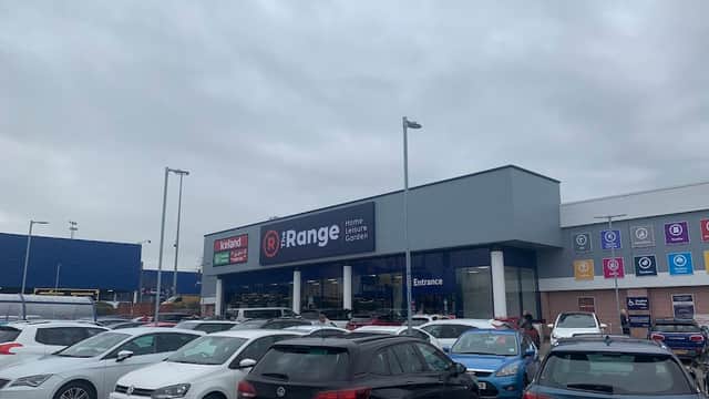 The Range store exterior with a large sign, surrounded by parked cars under a gray sky.