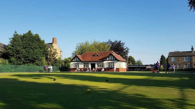 Darfield Park Bowling Club with green lawn, clubhouse, and people playing in the background under a clear blue sky.