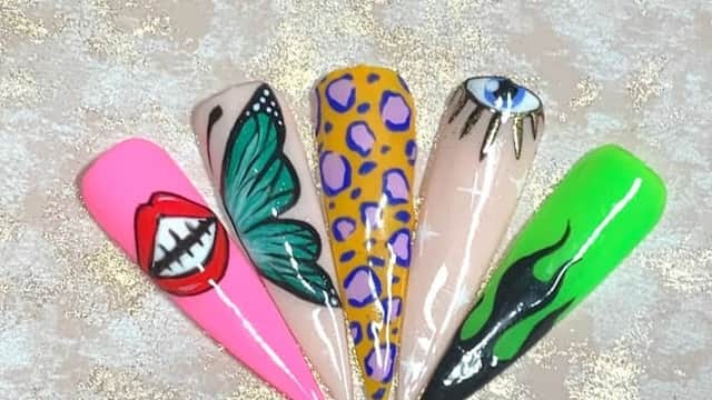 Colorful nail art showcasing designs like lips, a butterfly, leopard print, an eye, and abstract patterns on long nails.