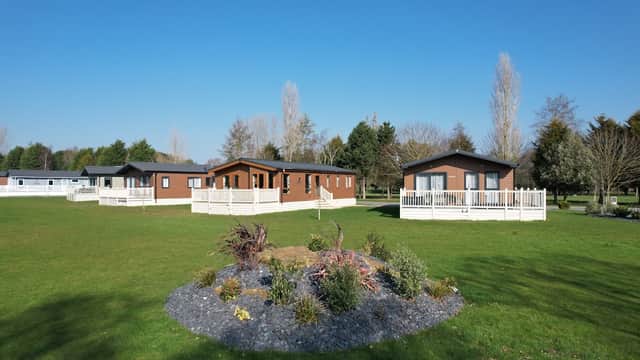 Lush green golf course with modern lodges and landscaped gardens under a clear blue sky.