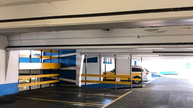 Empty car park with white and blue walls, yellow lines, and parked cars in Sheffield, Yorkshire.