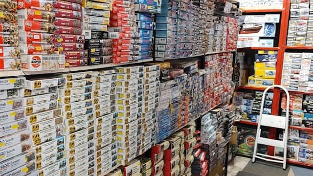 A narrow aisle lined with shelves stacked high with model kits and boxes in a well-organized store.