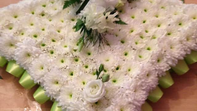A floral arrangement featuring white flowers and green accents, artfully arranged on a textured base.