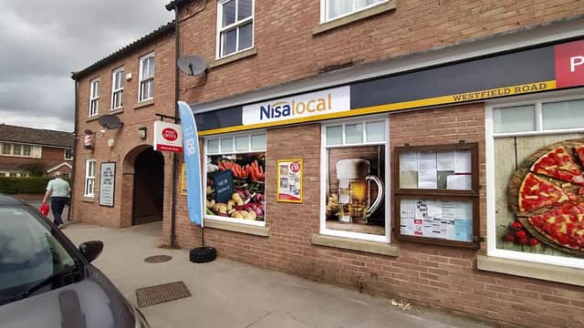 Nisa Local store exterior with a blue banner, posters of food and drinks, and a parked car on a street in Tockwith.