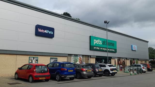 Exterior of Pets at Home shop in Harrogate, featuring a row of parked cars and cloudy skies.