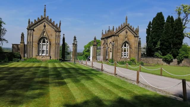 Gisburne Park Lodge features ornate stone buildings, manicured lawns, and a clear blue sky in Yorkshire.