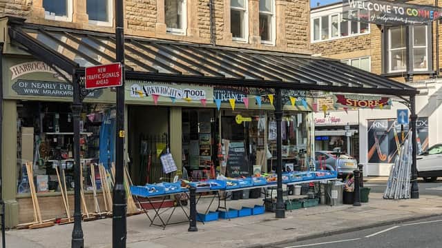 Mr Arkwright's Tool Emporium storefront with colorful signage, tools displayed outside, and a welcoming banner overhead.