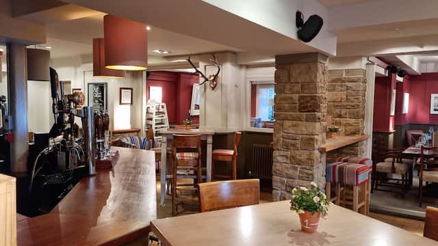 Cozy bar interior featuring wooden furniture, stone accents, and colorful seating in a warm, inviting atmosphere.