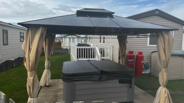 Hot tub under a gazebo with curtains, surrounded by holiday homes and a grassy area in Patrington, Yorkshire.