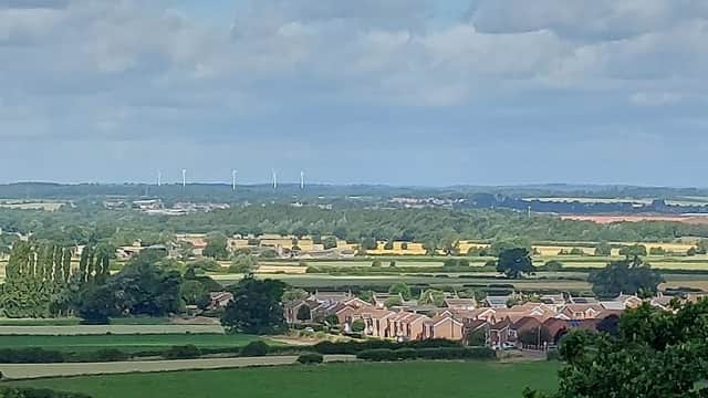 Rural landscape with fields, houses, and wind turbines under a partly cloudy sky in Hambleton, Selby, Yorkshire.