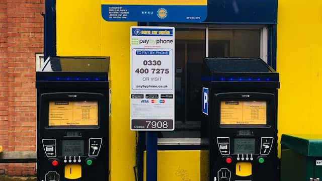 Pay & Display parking machines with a yellow sign detailing charges and contact information in Redcar and Cleveland.