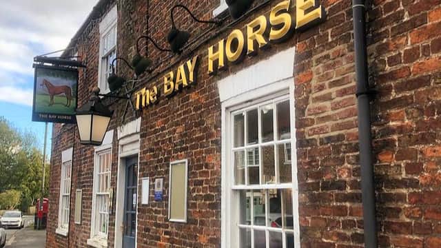 The Bay Horse pub features a brick facade, large windows, and a sign with a horse logo in Cherry Burton, Yorkshire.