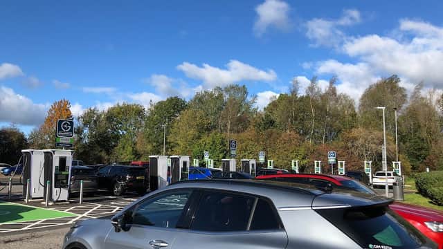 Electric vehicle charging stations at Scotch Corner Services with clear blue skies and autumn trees in the background.