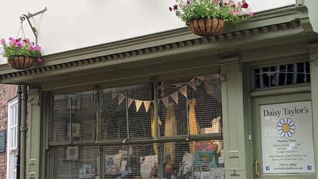 Charming gift shop with green facade, flower baskets, and a display of cards and gifts in York, Yorkshire.