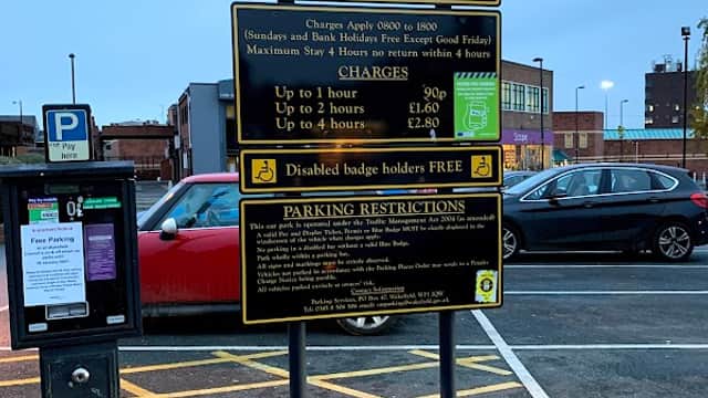 Welcome sign for Borough Road Car Park with parking charges and restrictions, surrounded by parked cars and buildings.