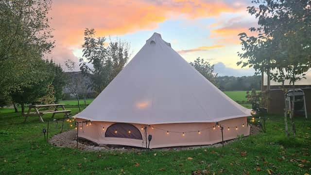 Glamping tent with soft lighting, surrounded by greenery and trees, under a colorful sunset sky in Hutton-le-Hole.