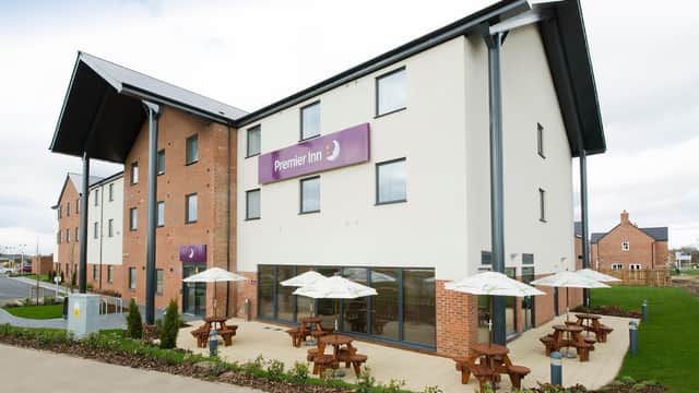 Premier Inn Thirsk hotel featuring a modern exterior, outdoor seating with umbrellas, and landscaped surroundings.