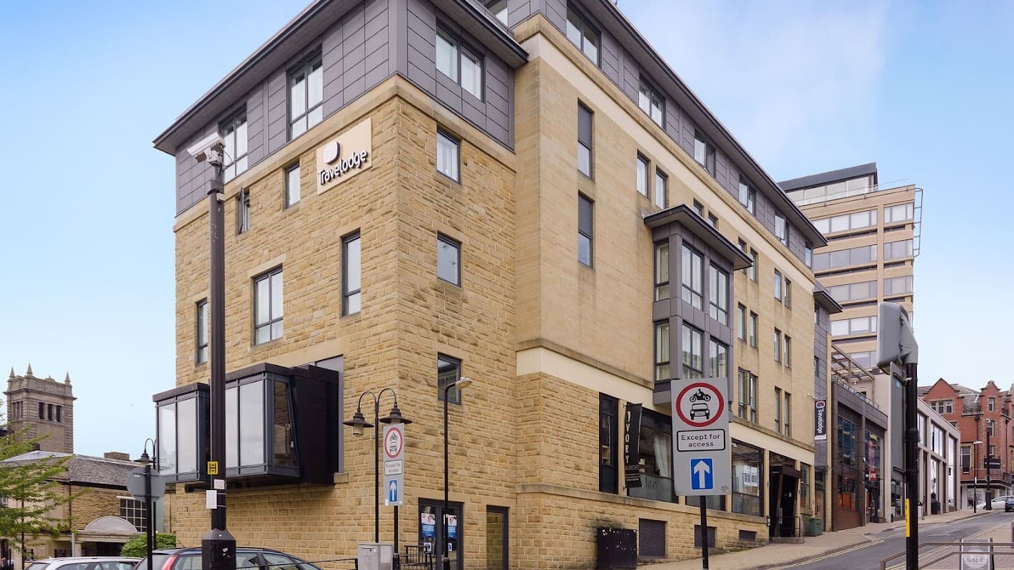 Stone building with a modern facade, featuring large windows and a Travelodge sign, located in Harrogate, Yorkshire.