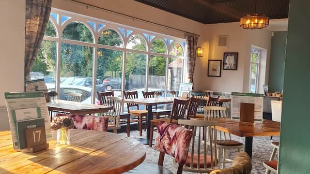 Cozy interior of Cromwell's Collingham with wooden tables, patterned chairs, and large windows letting in natural light.