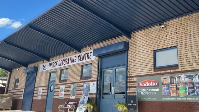 Thirsk Decorating Centre storefront with blue awning, large sign, and promotional banners on brick exterior.