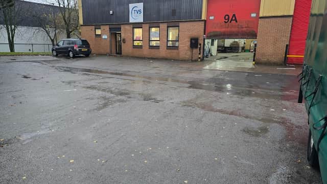 TVS SCS Courier Services building with red garage door, parked car, and wet ground in Maltby, Yorkshire.