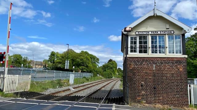 Kiveton Park Station building beside railway tracks, with blue sky and greenery in the background.