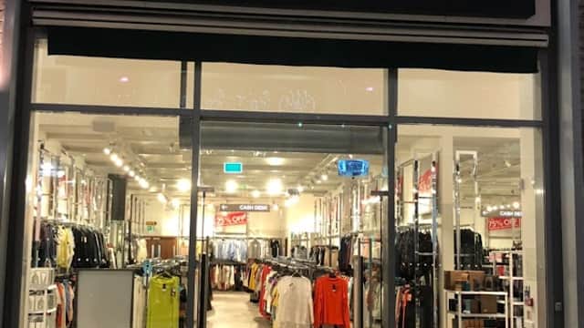 Brightly lit storefront of Next Outlet featuring various clothing displays and promotional signage in York, Yorkshire.