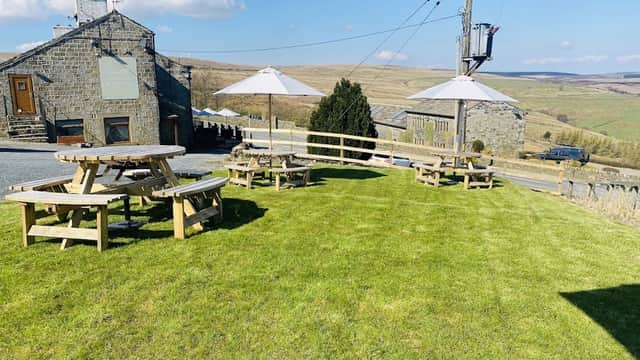 The Waggon & Horses Inn features outdoor seating on a grassy area with umbrellas and scenic Yorkshire hills in the background.