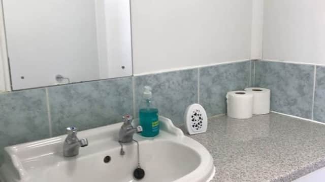 Clean sink area with a mirror, soap dispenser, and toilet paper rolls on a countertop.