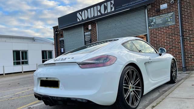 A sleek white sports car parked outside Source Sounds, a tech shop with a brick exterior and signage in Chapeltown.