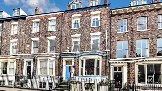 Victorian-style brick building with blue door, large windows, and flower pots, located on a street in York, Yorkshire.