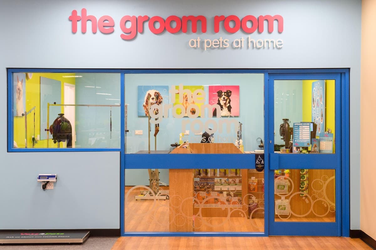 Brightly colored storefront of The Groom Room, featuring a large sign and glass entrance with pet grooming tools visible inside.
